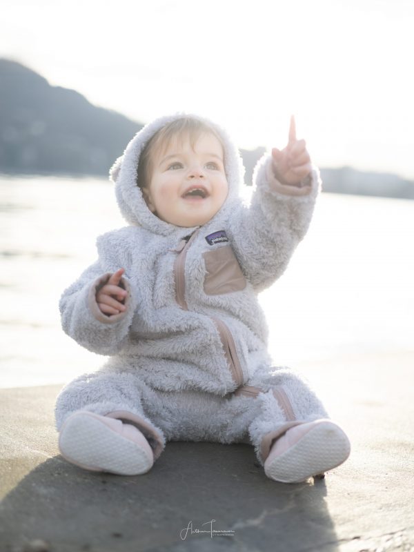 Bébé assis en extérieur lors d'une séance portrait, photographie en lumière naturelle.